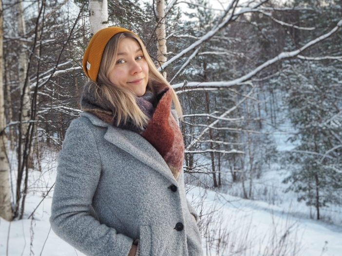 Milla Korkiakoski seisoo talvisessa maisemassa ja hymyilee.